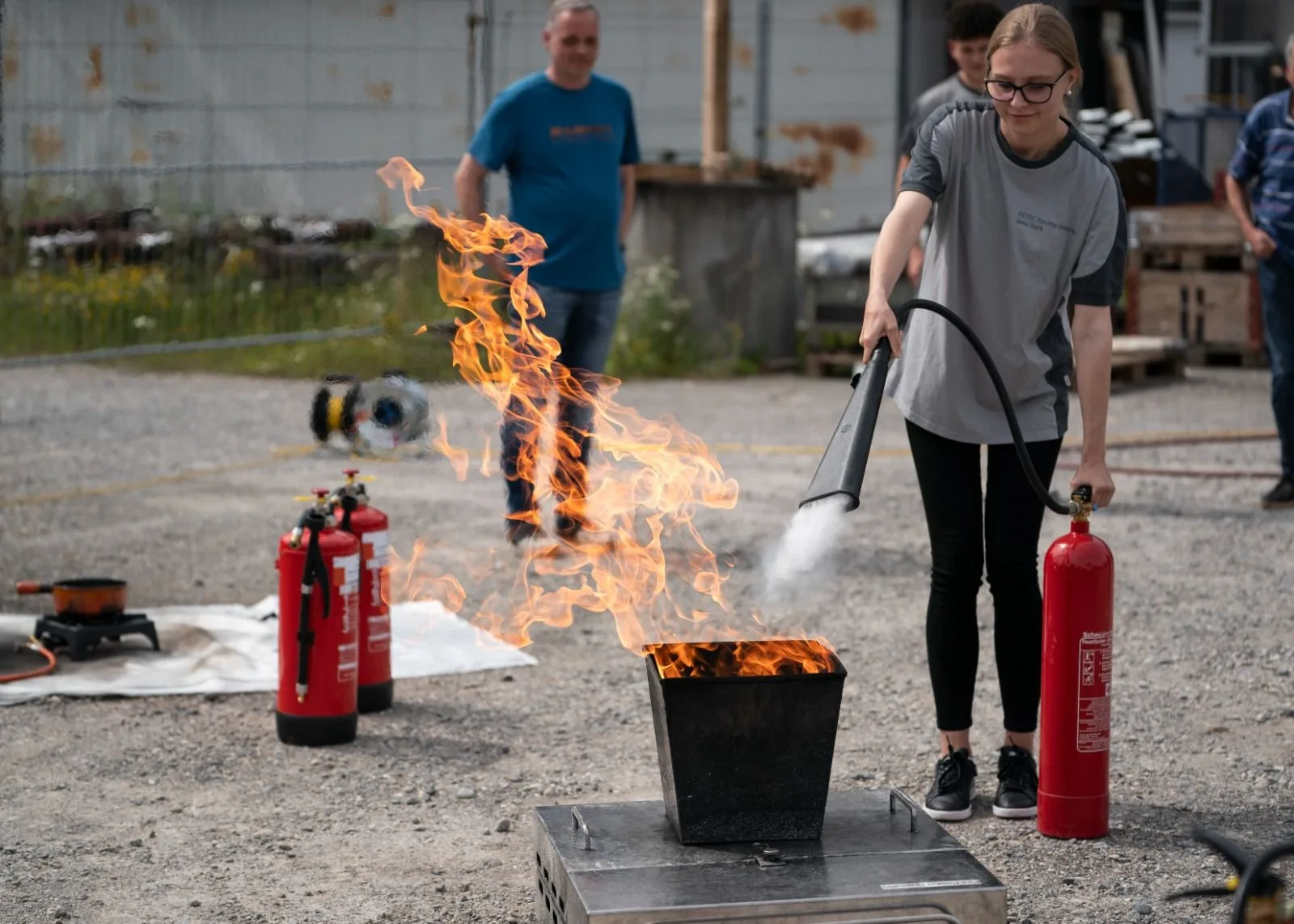 Teilnehmerin löscht einen Behälterbrand mit einem CO₂-Löscher